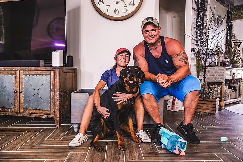 Happy couple with their protected Rottweiler at home