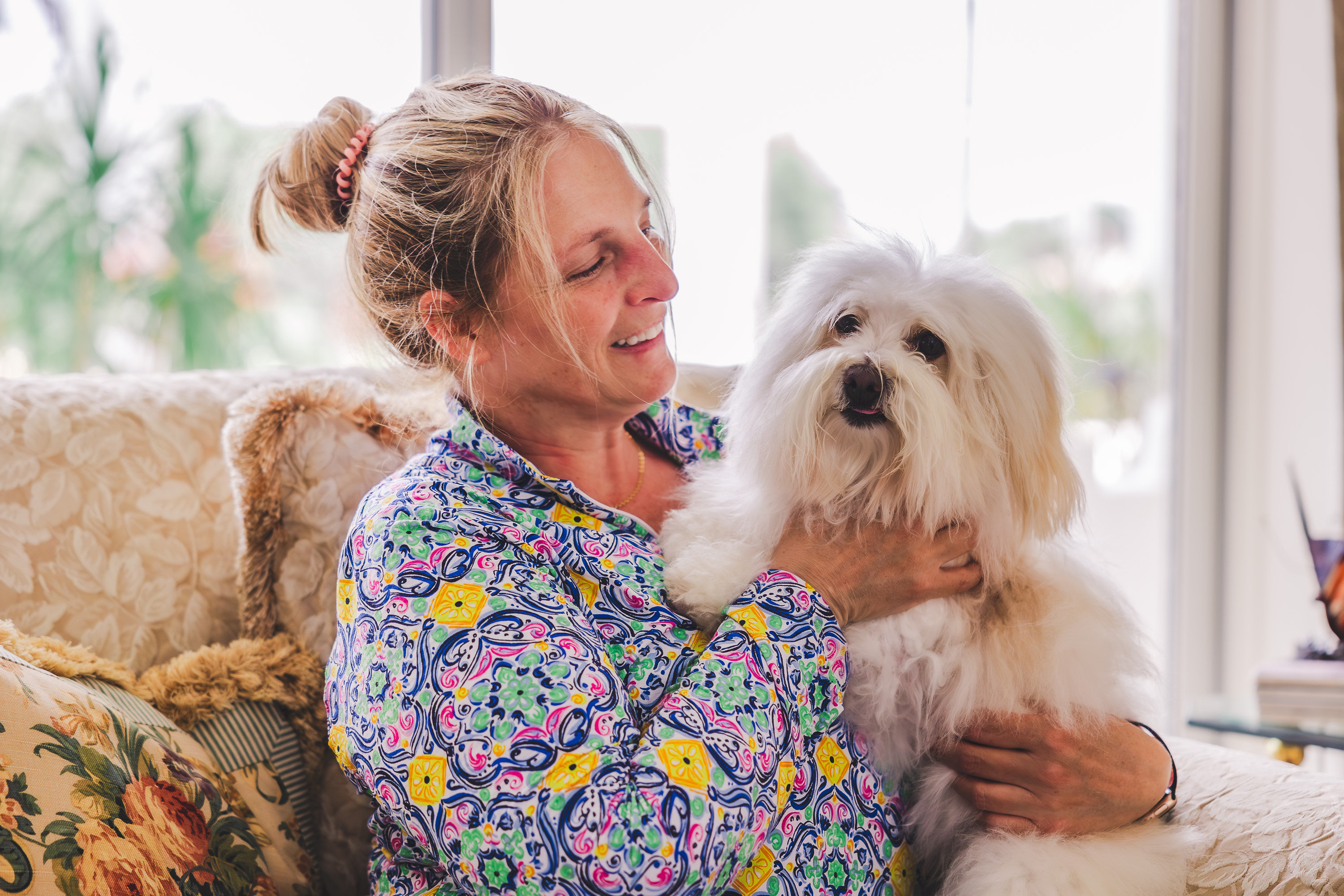 Woman cuddling with her safe small white dog